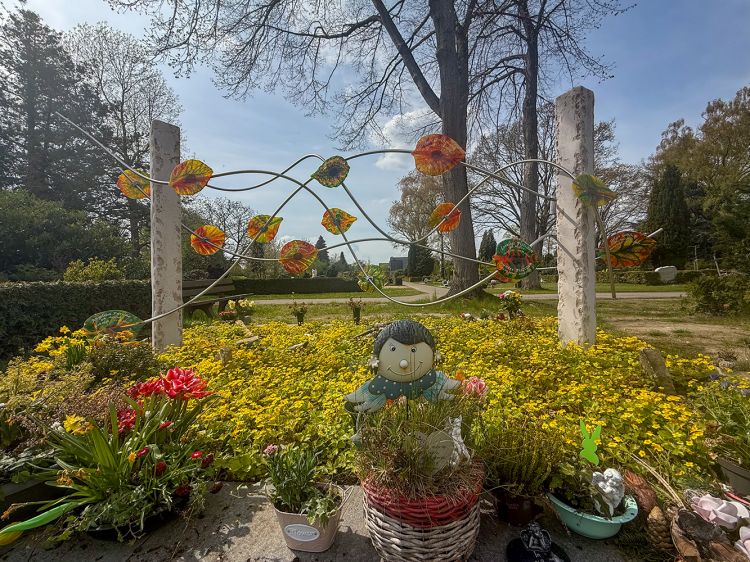 Gemeinschafts-Grabanlage mit Blumen und Figur im Vordergrund