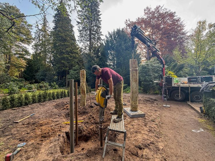 Arbeiter auf einer Trittstufe schlägt Rohre mit einer Pfahlramme in die Erde. Das Fundament für die Gemeinschaft-Grabanlage Arbeiter auf einer Trittstufe schlägt Rohre mit einer Pfahlramme in die Erde. Das Fundament für die Gemeinschaft-Grabanlage
