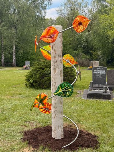 Kalkstein-Säule mit einer Spirale aus Edelstahl, daran sind 10 bunte Glasblätter installiert. Kalkstein-Säule mit einer Spirale aus Edelstahl, daran sind 10 bunte Glasblätter installiert.